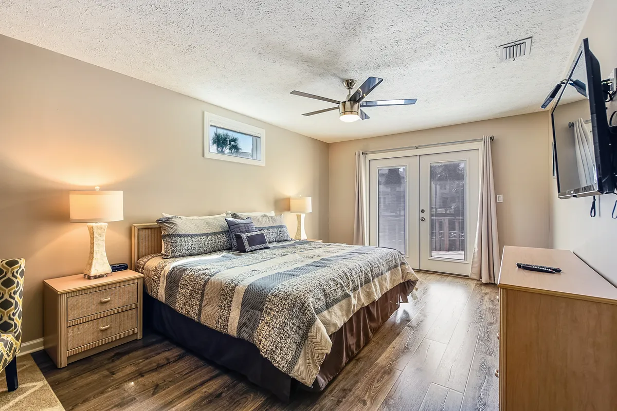 This image features a king-sized bed with two bedside lamps and sliding glass doors, creating a luxurious and tranquil atmosphere. The bed is beautifully made, and natural light filters through the space, evoking the statement about restful nights and private moments in the master suite.
